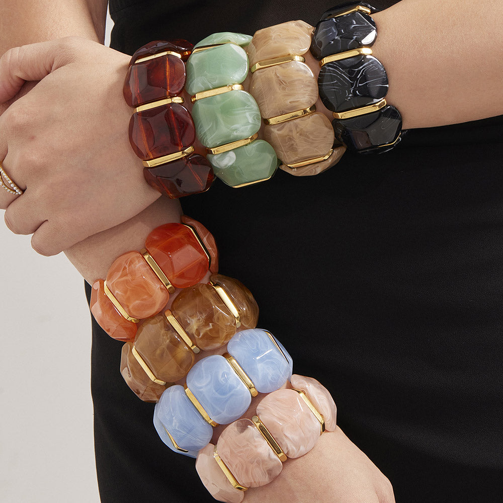 UMA MÃO USANDO VÁRIAS BRACELETES ELÁSTICAS COLORIDAS